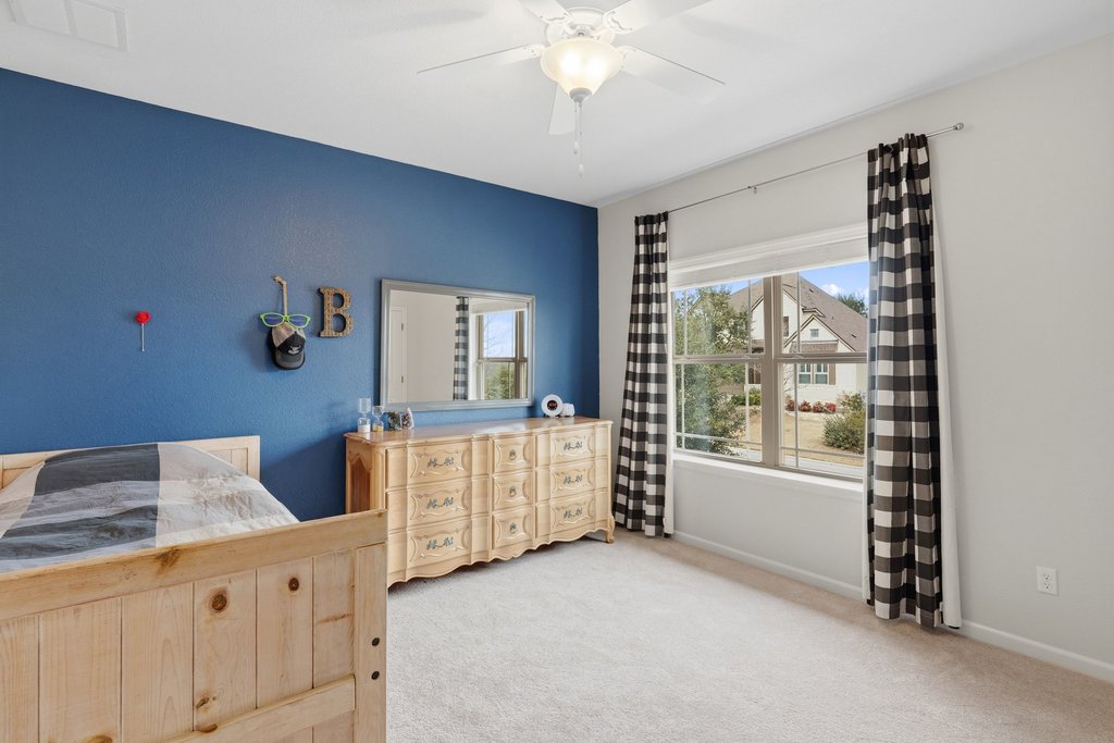 558 Merion Drive Austin, TX 78737 - Photo 27 of 40 a spacious bedroom with a bed and a chandelier