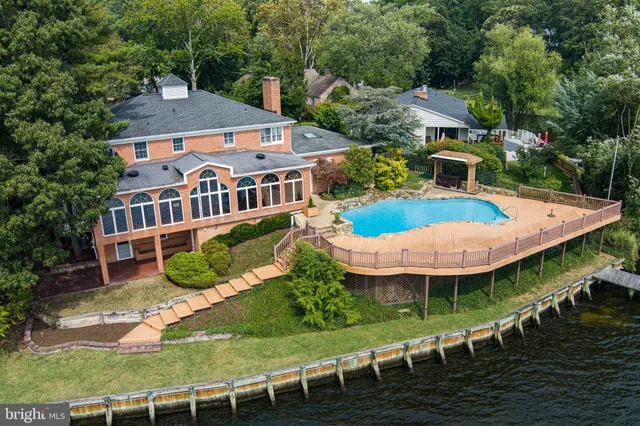 a view of a brick house with a yard plants and large tree