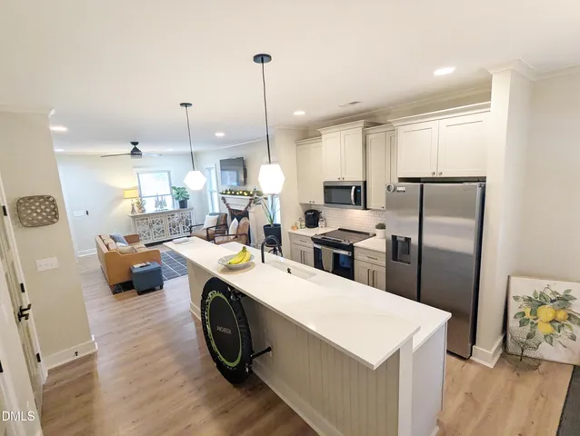 a kitchen with stainless steel appliances a table chairs wooden floors and a view of living room