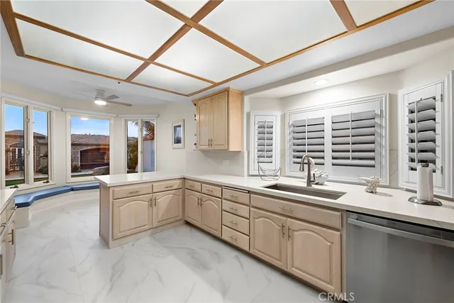 a large white kitchen with a sink and dishwasher with a large window