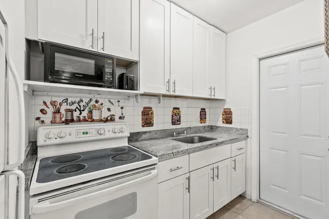a kitchen with stainless steel appliances granite countertop a stove a sink and a white cabinets