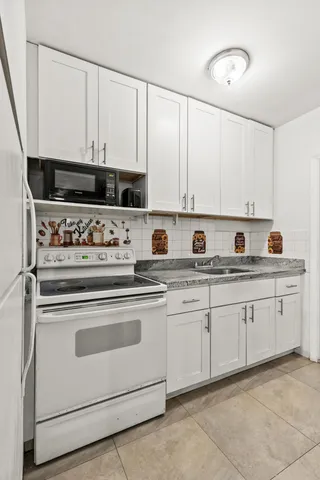 a kitchen with stainless steel appliances granite countertop white cabinets and a sink