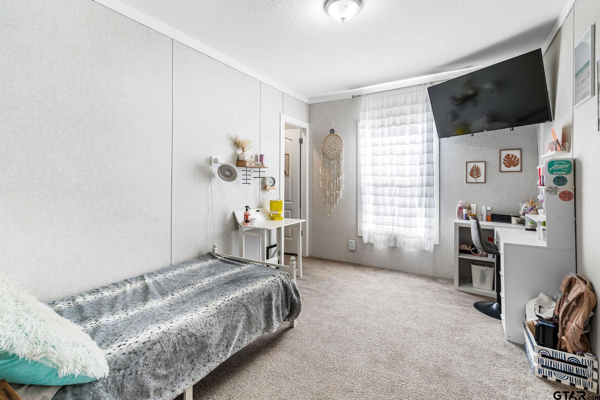 1255 Raintree Lakes Circle Big Sandy, TX 75755 - Photo 14 of 28 a bedroom with a bed a flat screen tv and a window