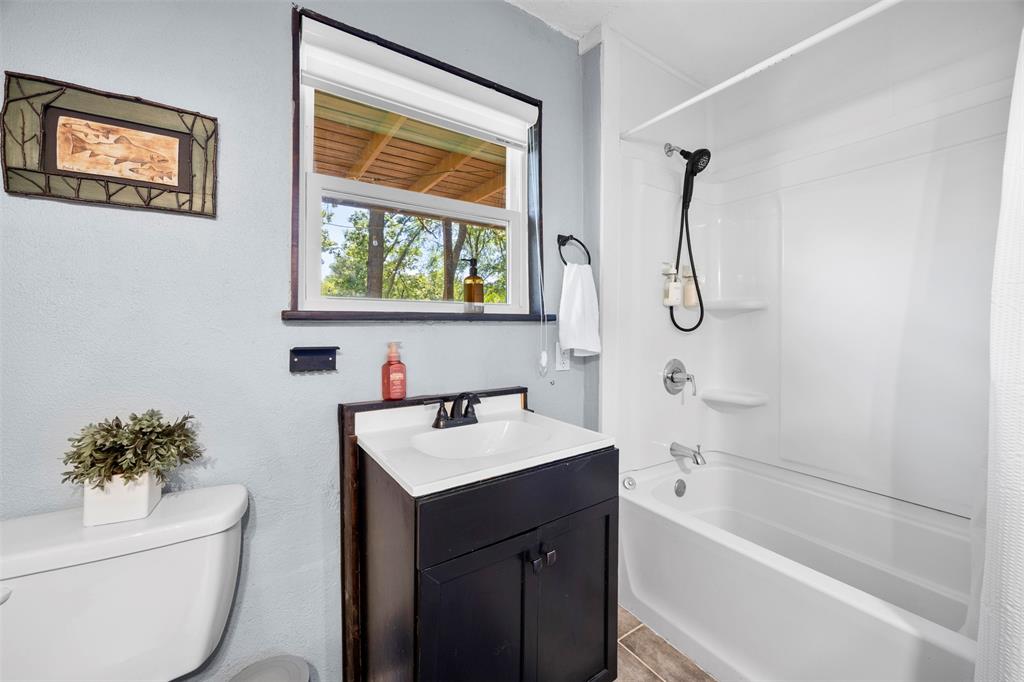 7110 Apache Circle Mabank, TX 75156 - Photo 16 of 39 Bathroom featuring a white bathtub and shower surround, a dark wood-finish vanity with an integrated sink, and wood-finish flooring
