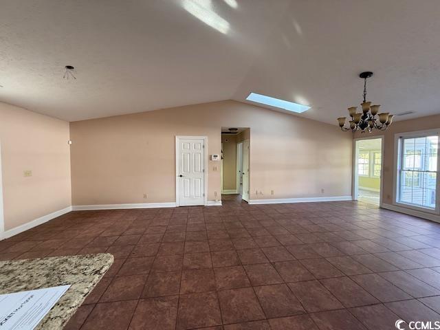 983 Nottingham Lakes Road Conway, SC 29526 - Photo 5 of 27 Empty room featuring lofted ceiling, a skylight, a chandelier, and dark tile patterned floors