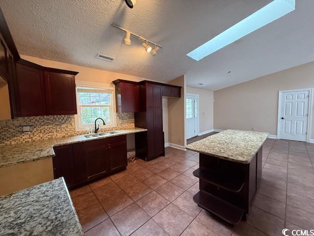 983 Nottingham Lakes Road Conway, SC 29526 - Photo 7 of 27 Kitchen featuring dark brown cabinetry, a center island, light stone countertops, open shelves, and vaulted ceiling