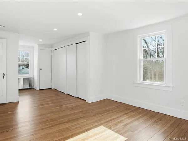 an empty room with wooden floor cabinet and windows