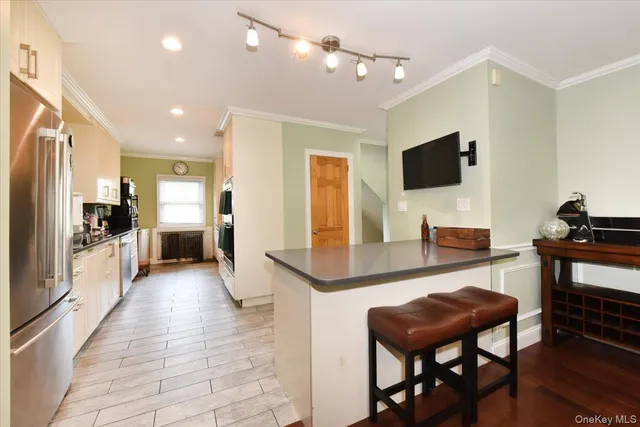 a living room with stainless steel appliances furniture a flat screen tv and kitchen view