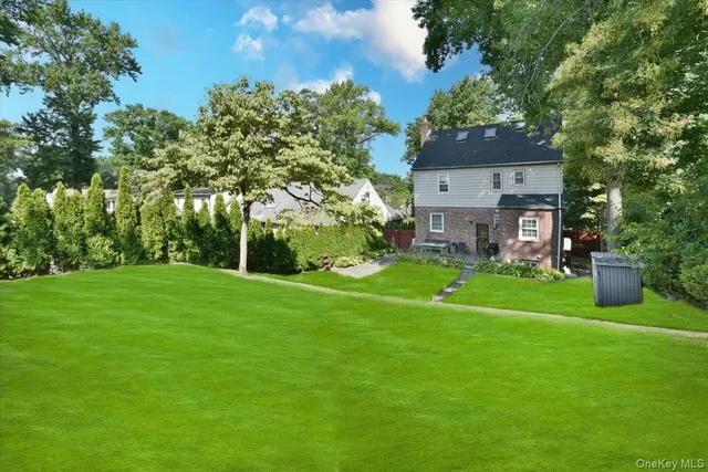 a view of a big house with a big yard and large trees