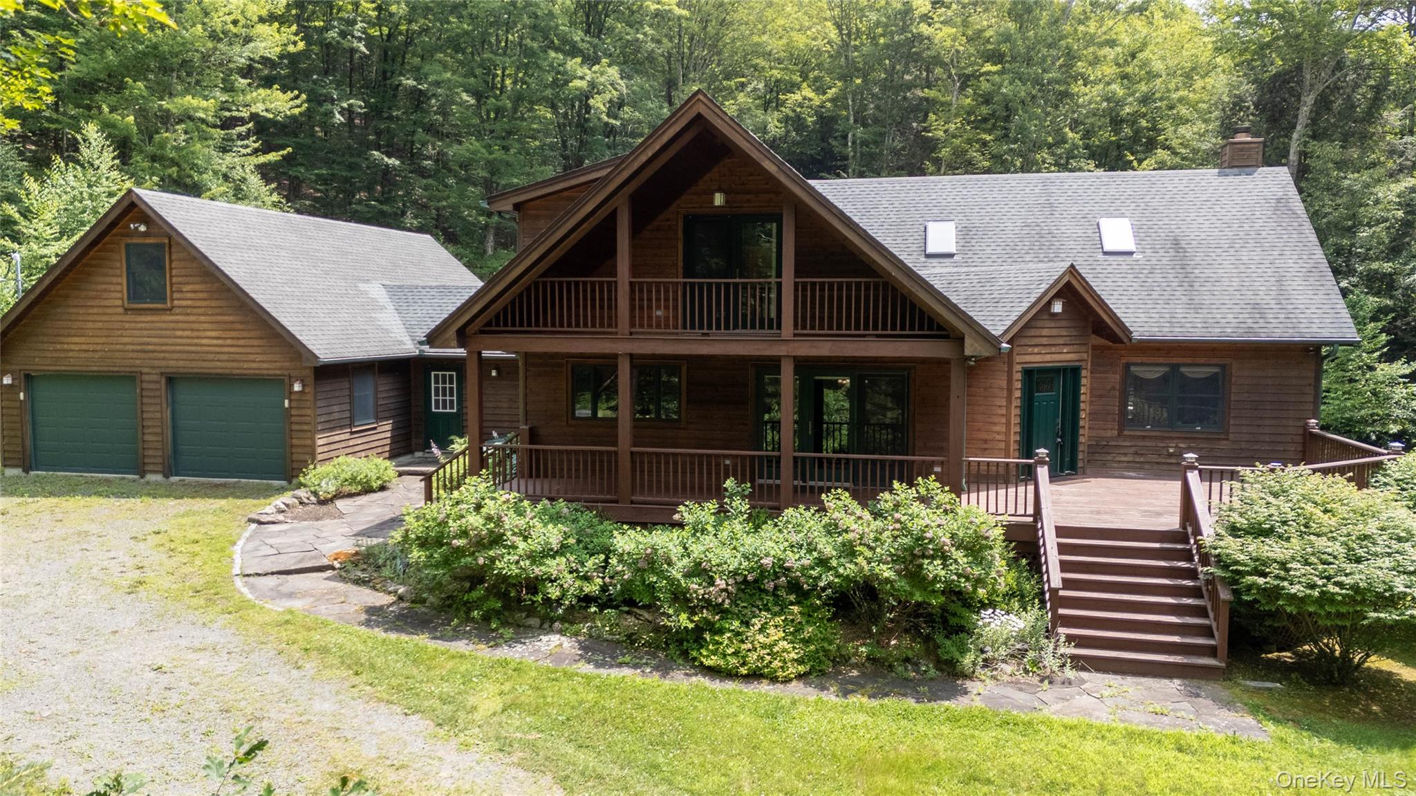 Chalet / cabin featuring covered porch, a garage, stairway, and a shingled roof