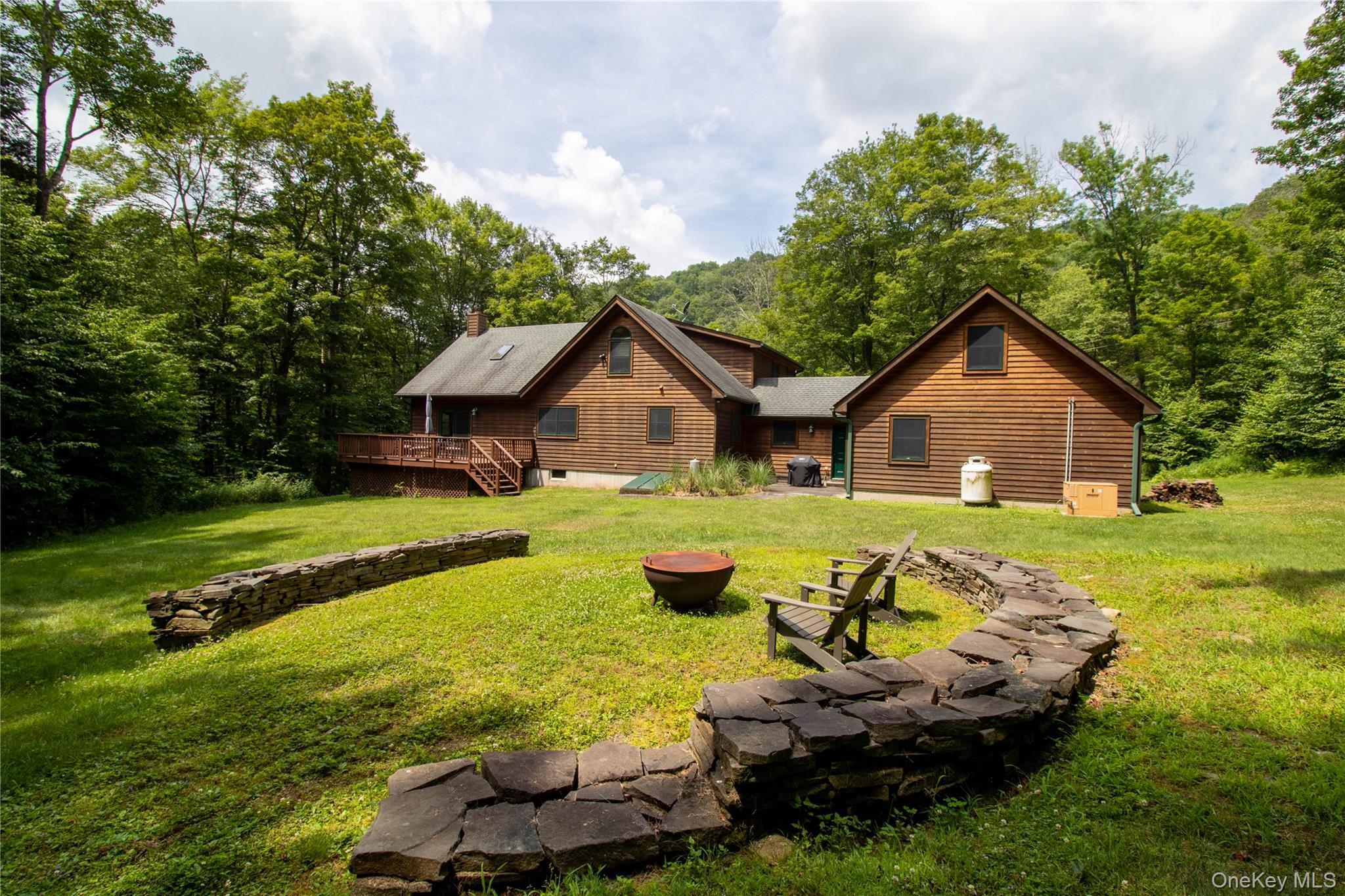 384 Morton Hill Road Roscoe, NY 12776 - Photo 5 of 27 Back of property with a deck, a lawn, a chimney, a forest view, and an outdoor fire pit