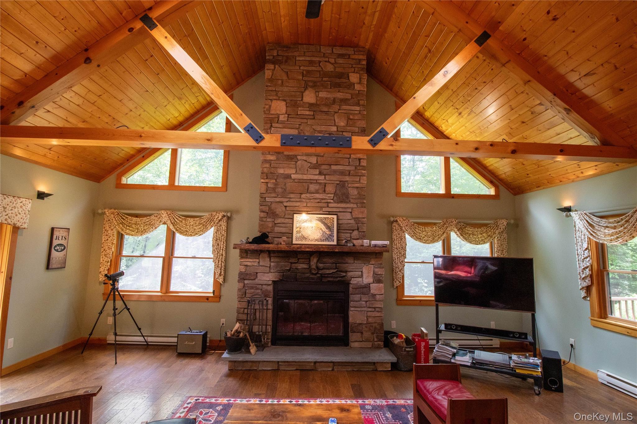 384 Morton Hill Road Roscoe, NY 12776 - Photo 8 of 27 Living area with wood-type flooring, high vaulted ceiling, a wood ceiling with exposed beams, a fireplace, and baseboard heating