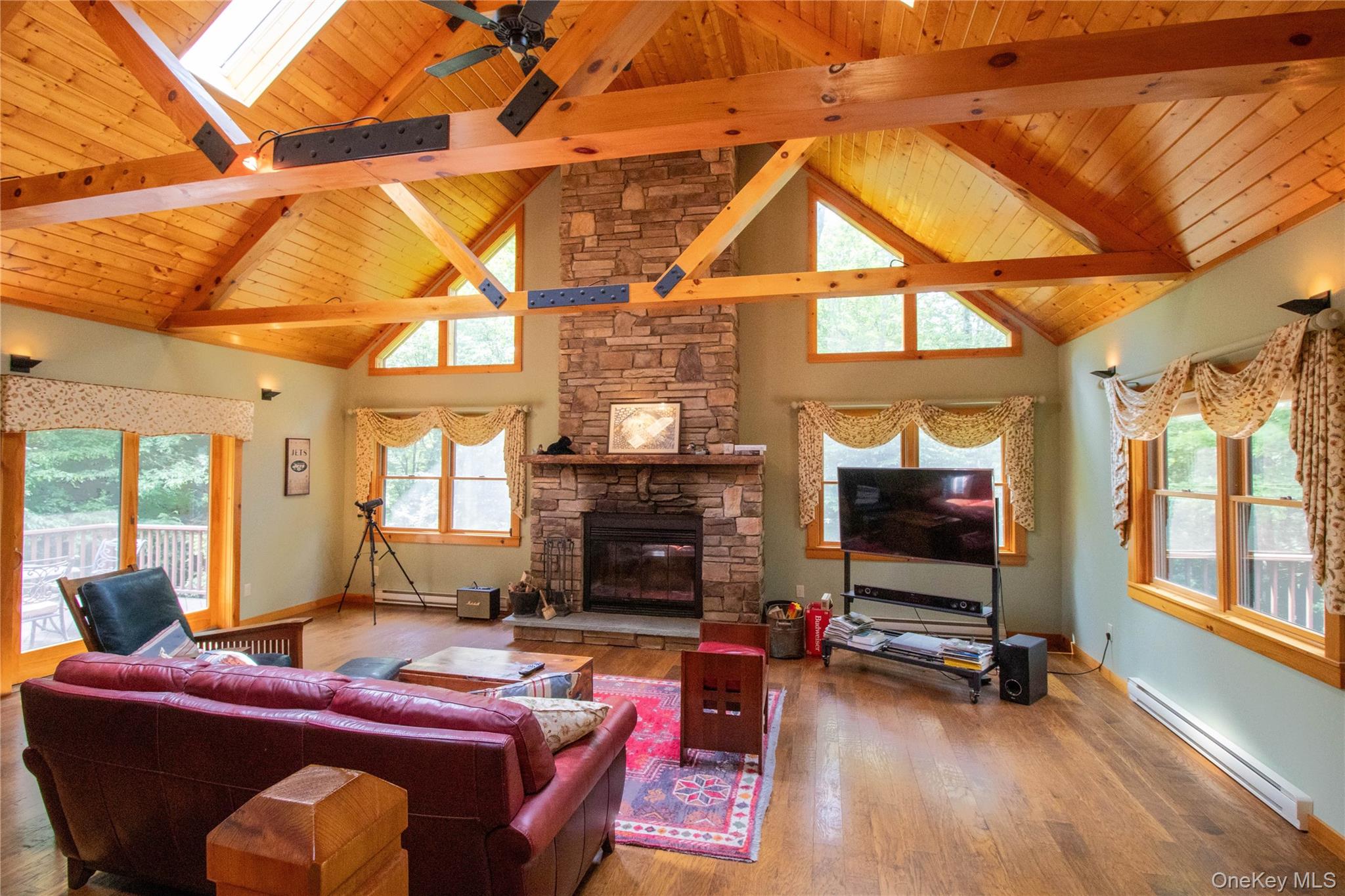 384 Morton Hill Road Roscoe, NY 12776 - Photo 9 of 27 Living area featuring a baseboard radiator, high vaulted ceiling, wood finished floors, a fireplace, and a skylight