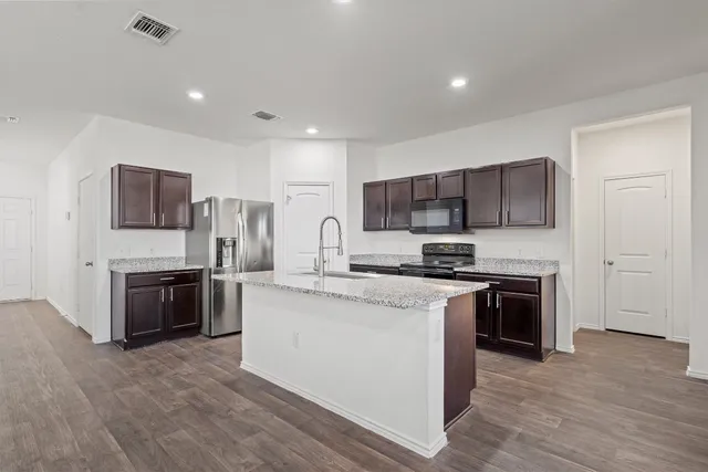 a kitchen with stainless steel appliances granite countertop a stove top oven a sink and a refrigerator