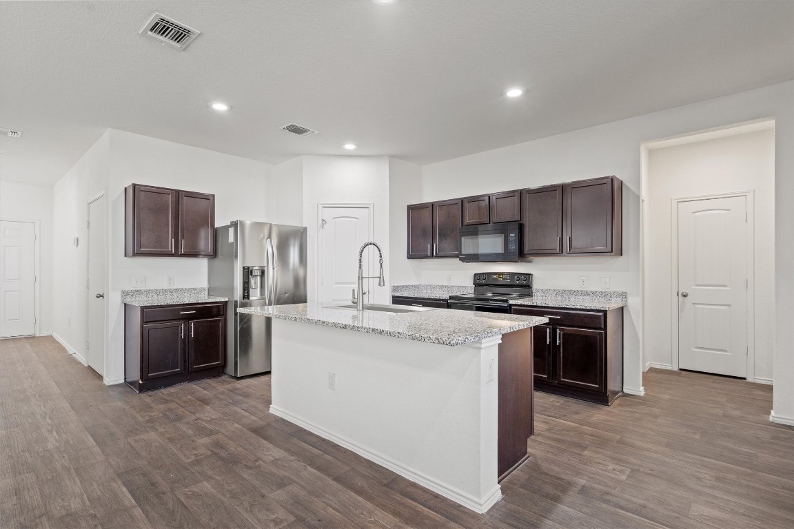 11908 Pyrite Road Manor, TX 78653 - Photo 8 of 35 a kitchen with stainless steel appliances granite countertop a stove top oven a sink and a refrigerator