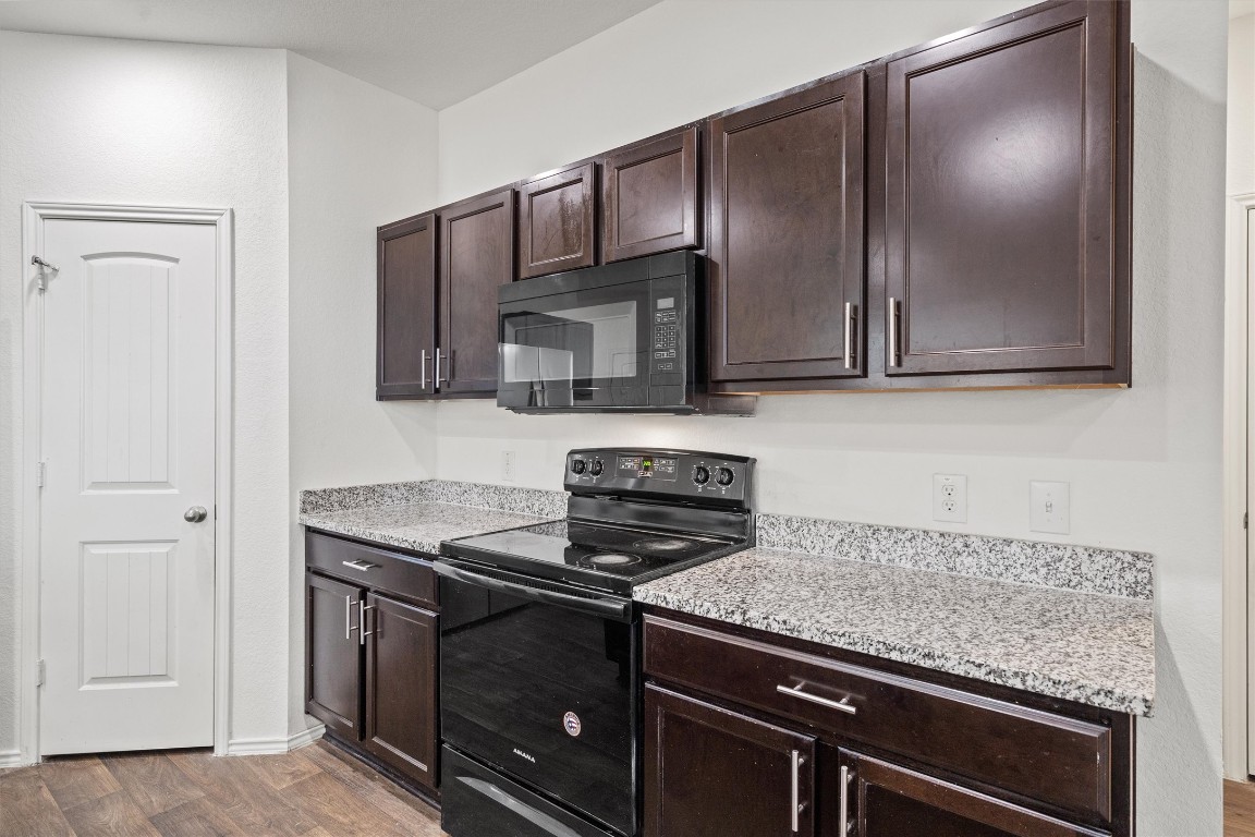 11908 Pyrite Road Manor, TX 78653 - Photo 10 of 35 a kitchen with granite countertop stainless steel appliances a stove microwave and sink