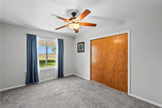an empty room with a window and a ceiling fan