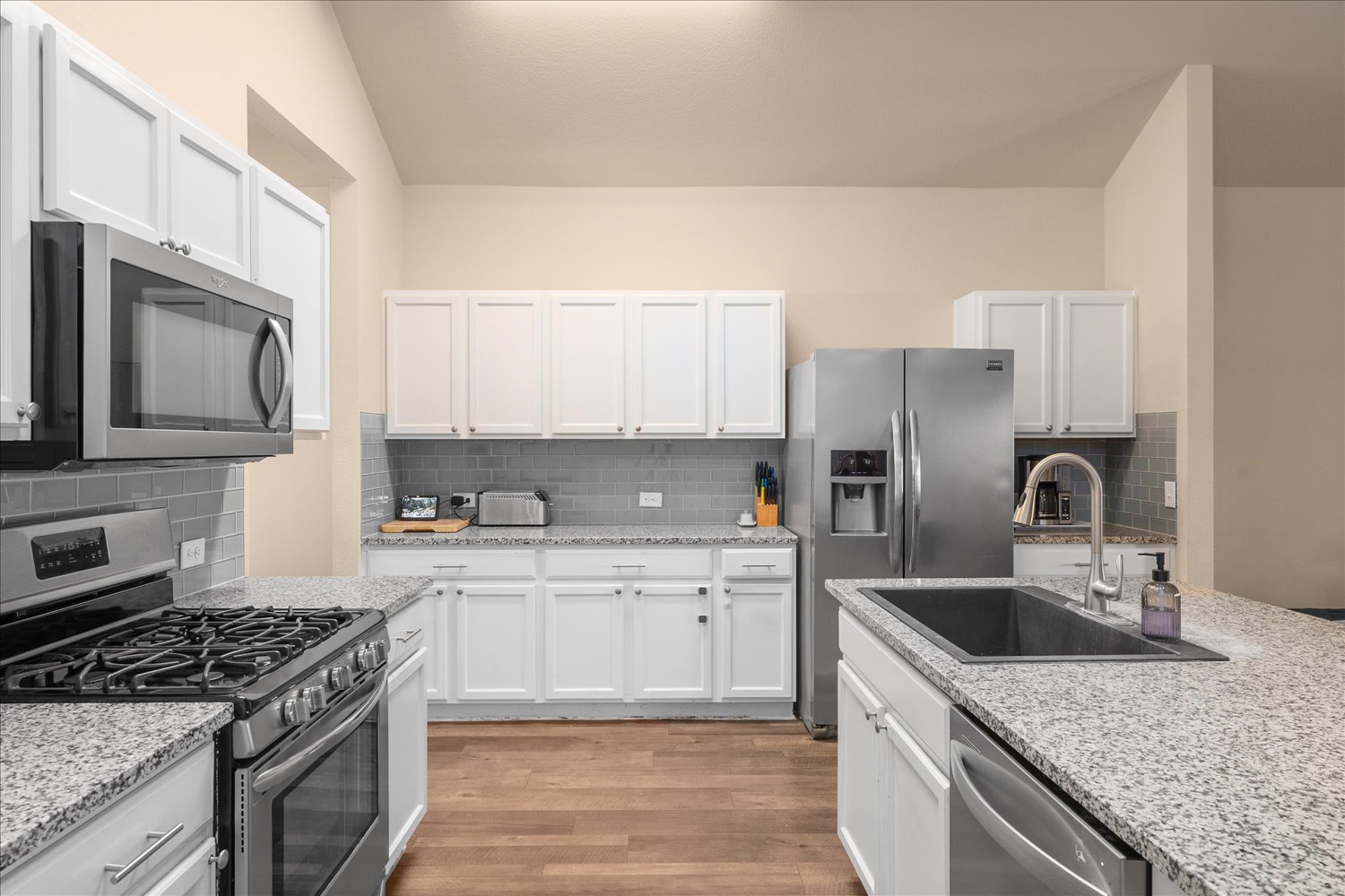 717 Kaluga Trail Leander, TX 78641 - Photo 12 of 40 a kitchen with stainless steel appliances granite countertop a sink stove and refrigerator