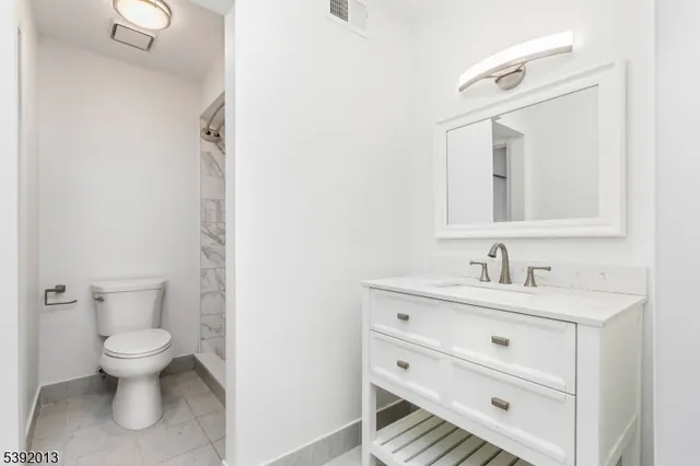 a bathroom with a toilet sink vanity and mirror
