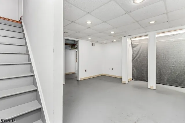 a view of an empty room with stairs and a bathroom