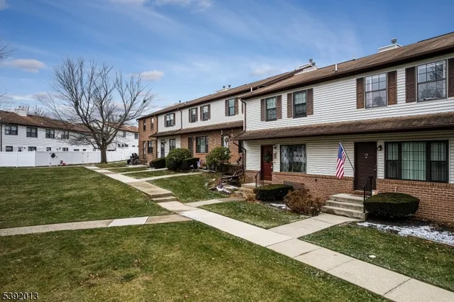 a front view of a residential apartment building with yard and green space
