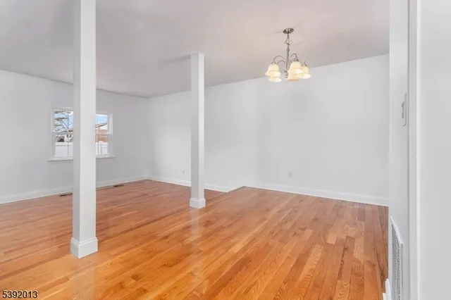 an empty room with wooden floor and ceiling fan