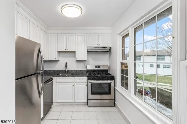 a kitchen with stainless steel appliances granite countertop a refrigerator sink and stove