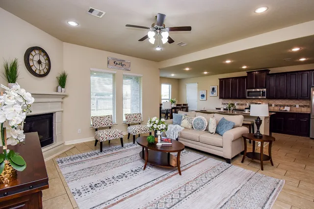 a living room with furniture a fireplace and a ceiling fan