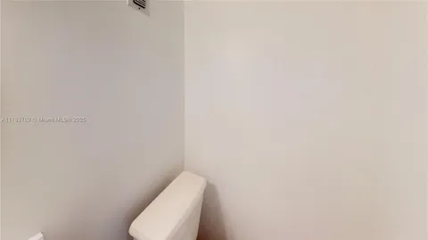 a white toilet sitting next to a white wall