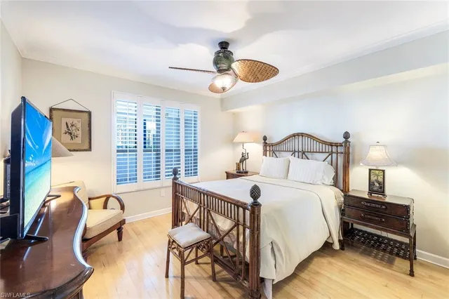 a bedroom with a bed a desk and chair with wooden floor