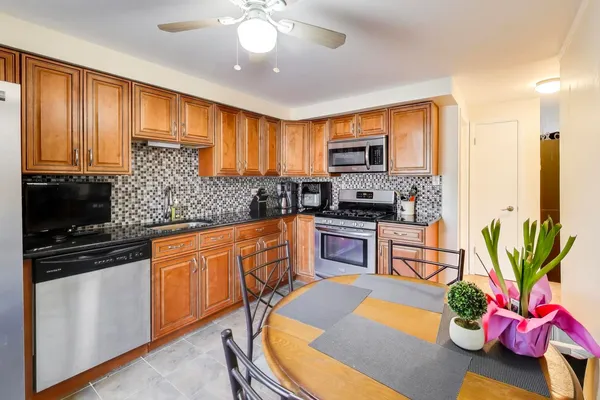 a kitchen with stainless steel appliances granite countertop a refrigerator a stove a sink a counter space and dining table
