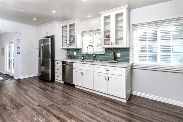 a kitchen with stainless steel appliances granite countertop a sink cabinets and wooden floor
