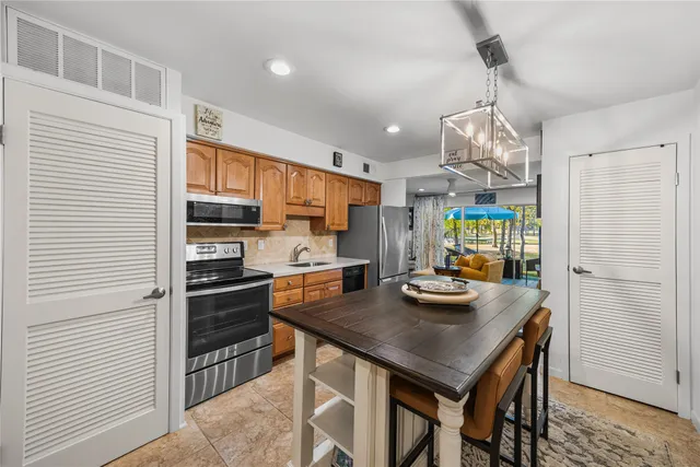 a kitchen with stainless steel appliances kitchen island granite countertop a table chairs in it and wooden floors