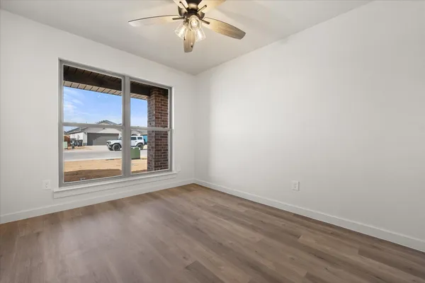 an empty room with wooden floor fan and windows