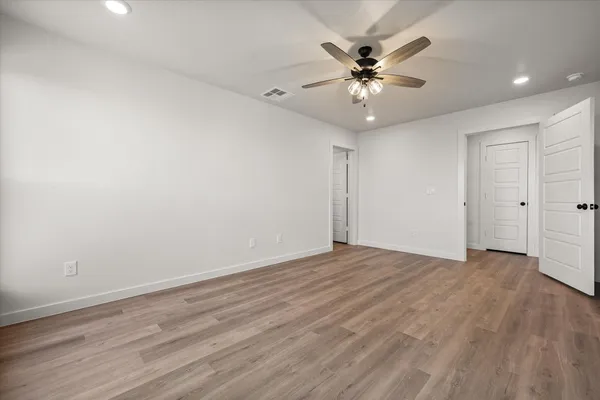 a view of an empty room with cabinet and a ceiling fan
