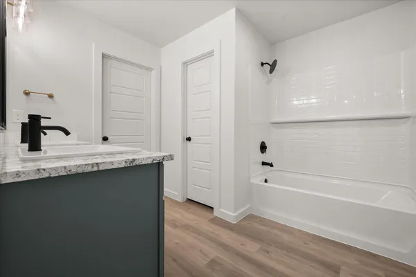 a bathroom with a granite countertop sink two mirror and a bathtub