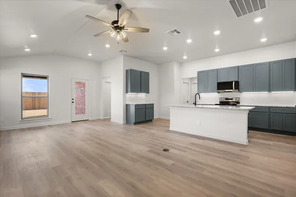 a view of kitchen with microwave a stove and white cabinets
