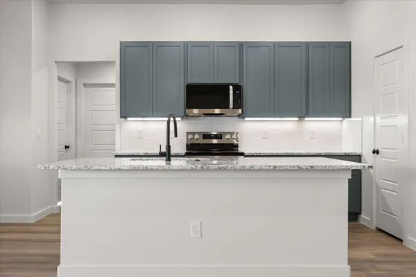 a kitchen with a sink a microwave a refrigerator and cabinets