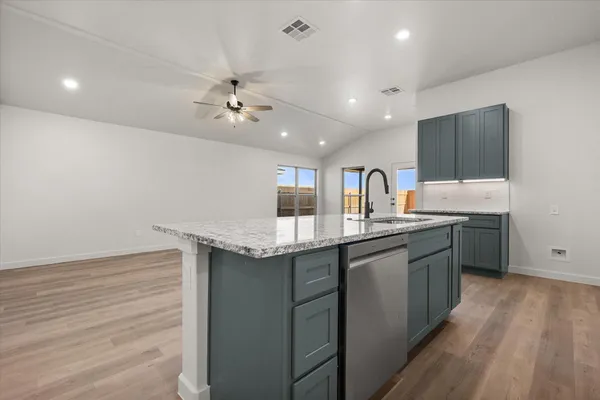 a kitchen with granite countertop a sink cabinets and wooden floor