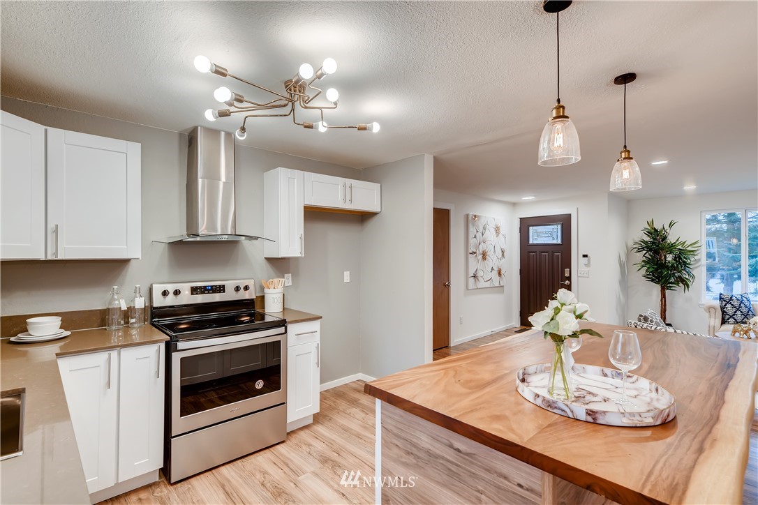 31404 3rd Place South Federal Way, WA 98003 - Photo 8 of 24 a kitchen with stainless steel appliances granite countertop a stove a sink a dining table and chairs with wooden floor