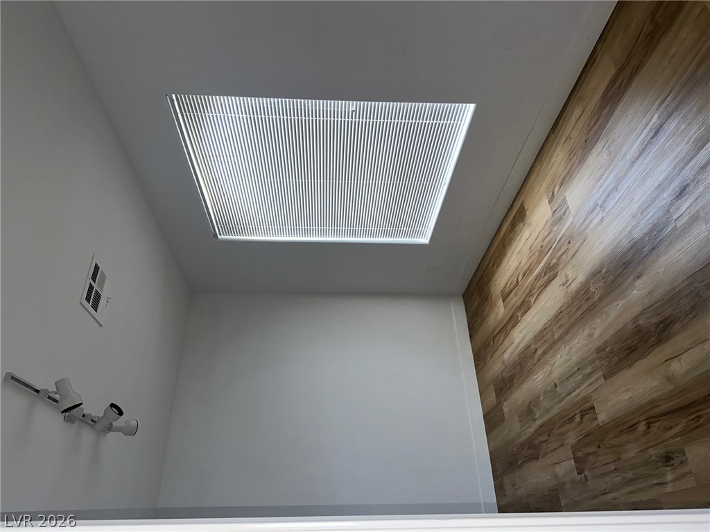 2050 West Warm Springs Road, Unit 1323 Henderson, NV 89014 - Photo 6 of 10 A striking wall featuring rich wood-look paneling adds warmth to this versatile space, illuminated by a large ceiling window.