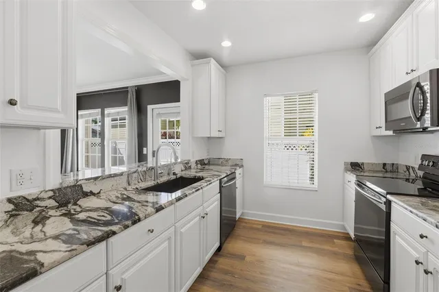 a kitchen with stainless steel appliances granite countertop a stove top oven a sink and a refrigerator