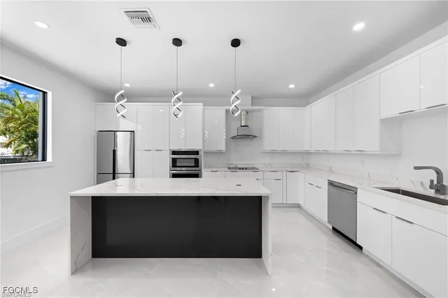 a kitchen with a sink a center island stainless steel appliances and cabinets