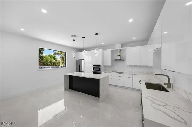 a large white kitchen with kitchen island a sink stainless steel appliances and cabinets