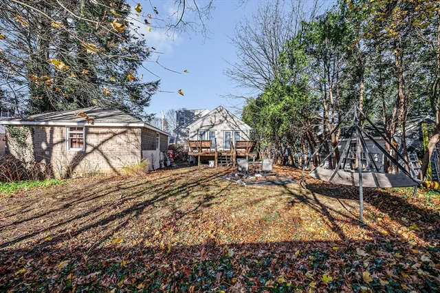 a backyard of a house with large trees and wooden fence