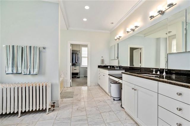 a large white kitchen with granite countertop a sink white cabinets and appliances