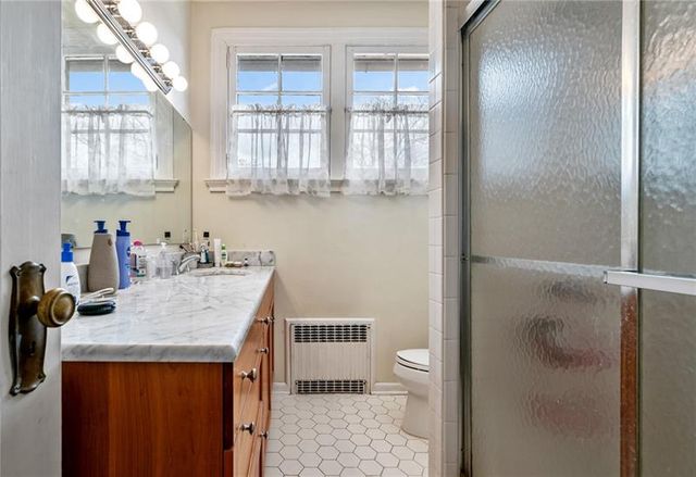 a bathroom with a granite countertop sink a toilet a window and shower