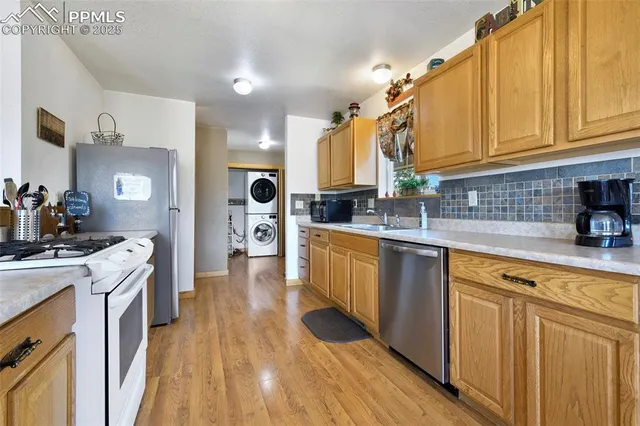 a kitchen with stainless steel appliances a sink dishwasher stove refrigerator and cabinets with wooden floor