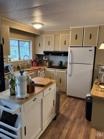 a kitchen with a sink a refrigerator and wooden floor