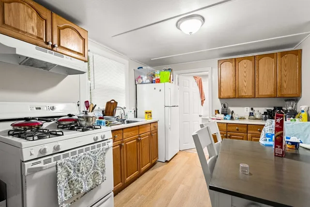 a kitchen with stainless steel appliances granite countertop a stove a sink dishwasher and white cabinets with wooden floor